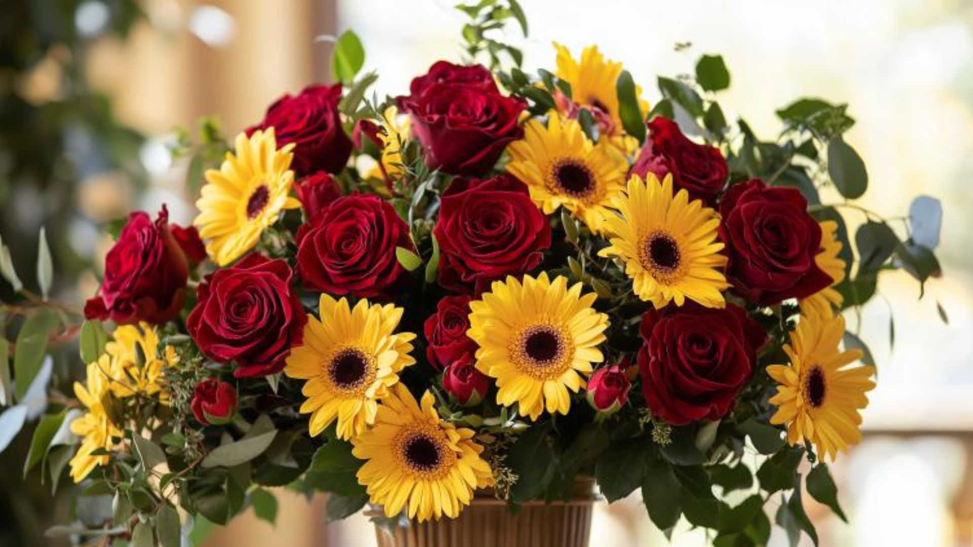 Composition florale funéraire colorée avec des roses rouges et des gerberas jaunes